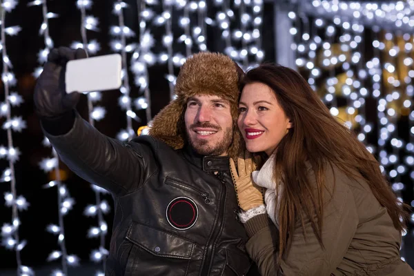 Smiling couple taking selfie with smart phone at ice rink — Stock Photo, Image