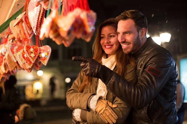 Heureux couple souriant à la recherche de bonbons coeurs pendant les vacances de Noël — Photo