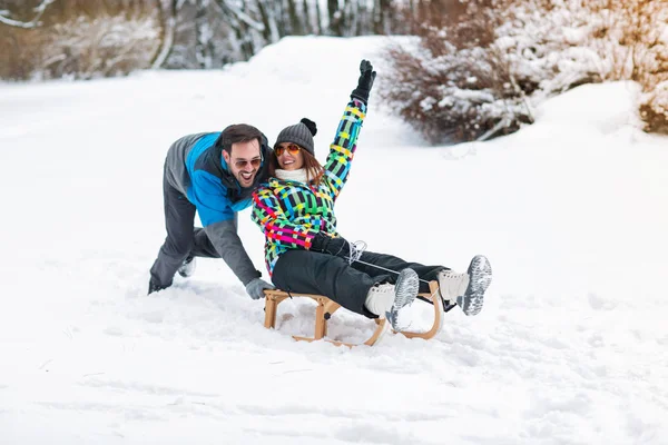 Smiling couple having fun on winter day and using sleigh — Stock Photo, Image