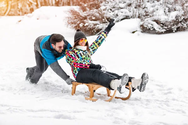 Young couple having fun on snowy day, sledding and smiling toget — Stock Photo, Image