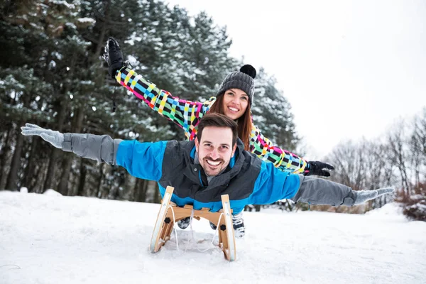 Smiling happy couple enjoy in sledding at snow winter day — Stock Photo, Image