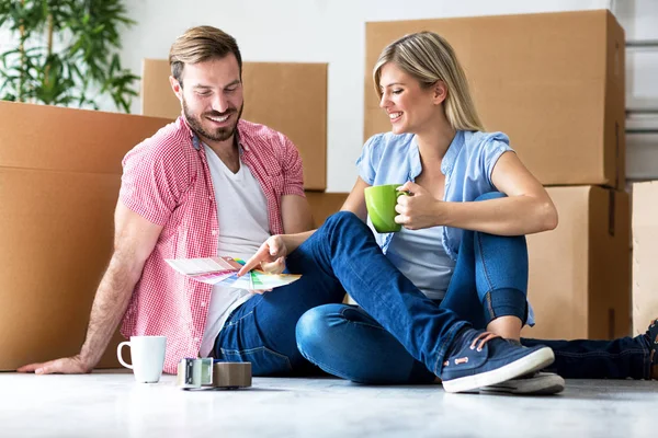 Feliz jovem casal se movendo em nova casa desempacotando caixas e choosi — Fotografia de Stock