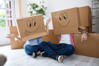Karton kutular giyen katta oturan komik mutlu çift