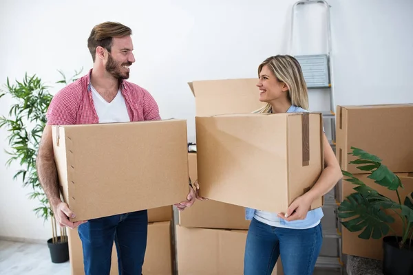 Lächelndes junges Paar mit Kartons und Päckchen für den Umzug — Stockfoto