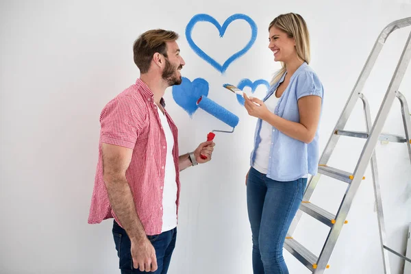 Preciosa sonrisa feliz pareja pintando su nuevo hogar — Foto de Stock