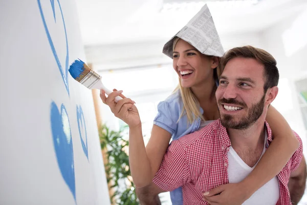 Jovem casal sorrindo paredes de pintura — Fotografia de Stock