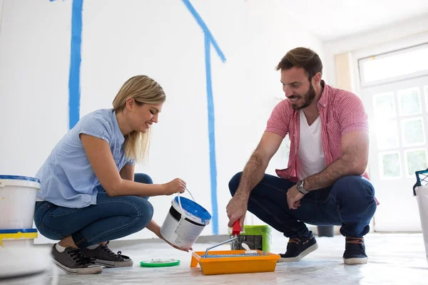 Joven pareja feliz eligiendo colores para pintar paredes — Foto de Stock