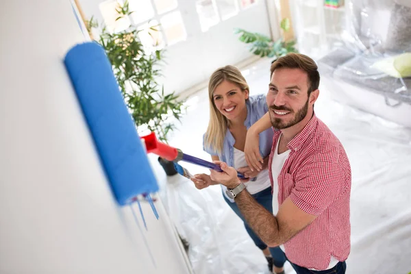 Joven pareja feliz pintando paredes en nuevo apartamento — Foto de Stock