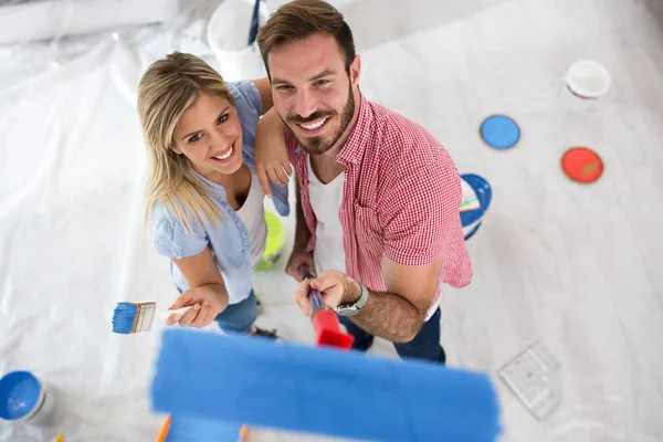 Atractiva joven sonriente pareja pintura nuevo hogar — Foto de Stock