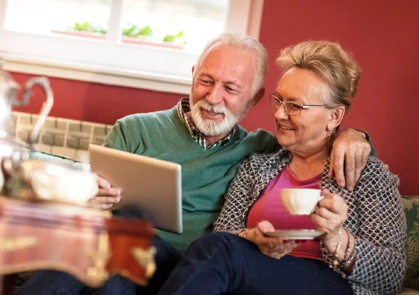 夫妇在客厅里喝茶的时候使用平板电脑 — 图库照片