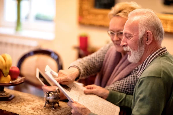 Äldre par ha kul samtidigt läsa tidningen och använda tabell — Stockfoto
