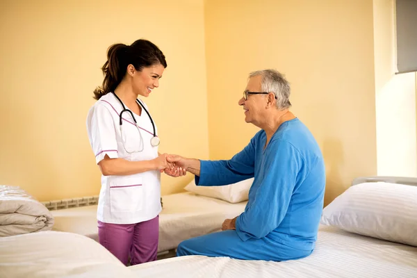 Beautiful young careful nurse talking and console patient at nur — Stock Photo, Image