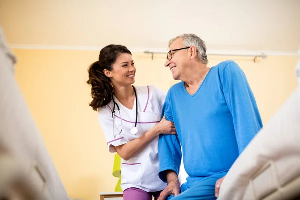 Nurse at nursing home helps senior man — Stock Photo, Image