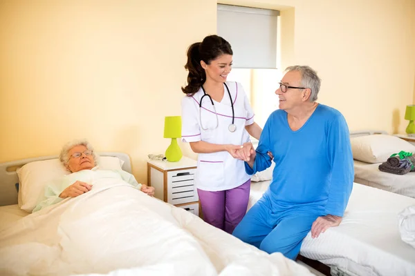 Nurse at nursing home helps to senior man — Stock Photo, Image