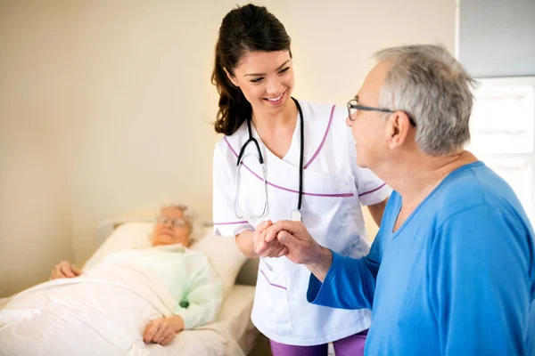 Smiling positive nurse worries about senior patients — Stock Photo, Image