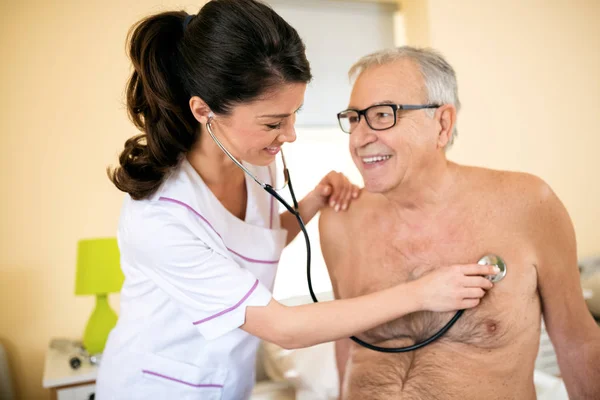 Jonge glimlachend positieve dokter examencommissie senior patiënt met stet — Stockfoto