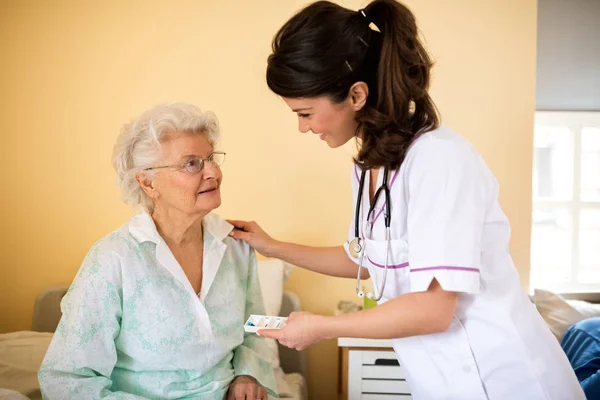 Oude senior vrouw wachten verpleegkundige drogs om haar — Stockfoto