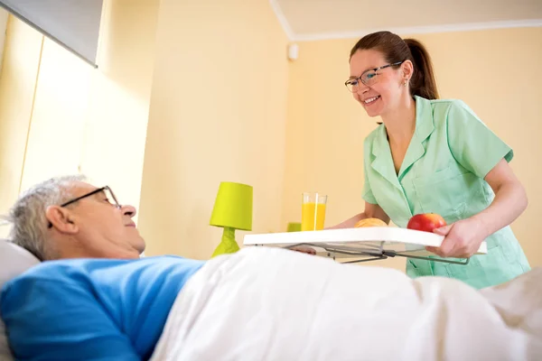 Careful nurse service a breakfasr to od patient — Stock Photo, Image