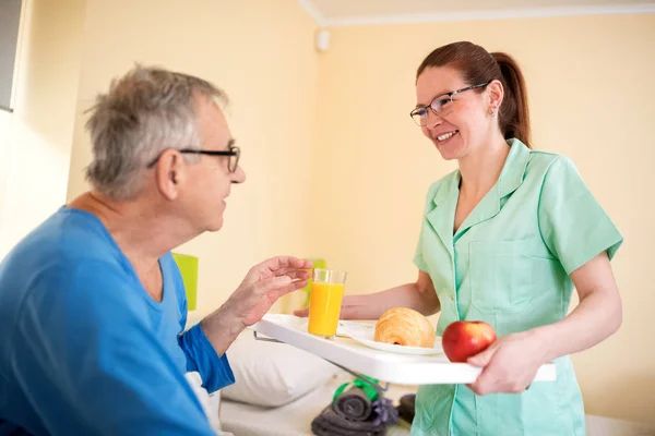 Happy Old Senior Man Looking Careful Nurse While She Brings — Stock Photo, Image