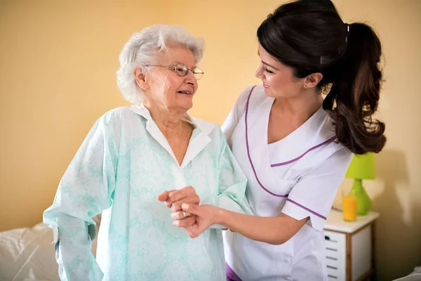 Helps old senior woman to walk with help of crutches — Stock Photo, Image