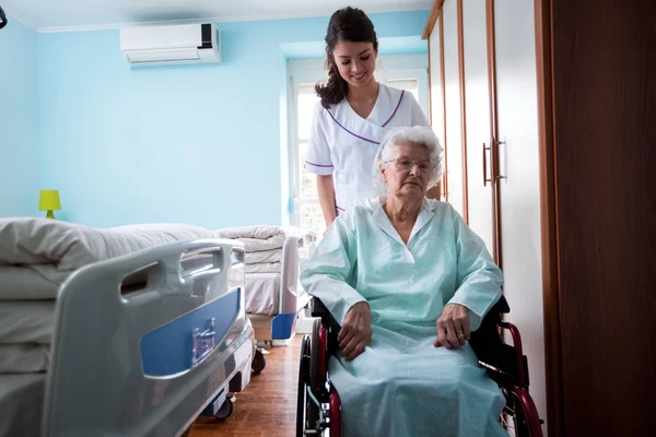 Nursing home, nurse goes outside with old woman at wheelchair — Stock Photo, Image