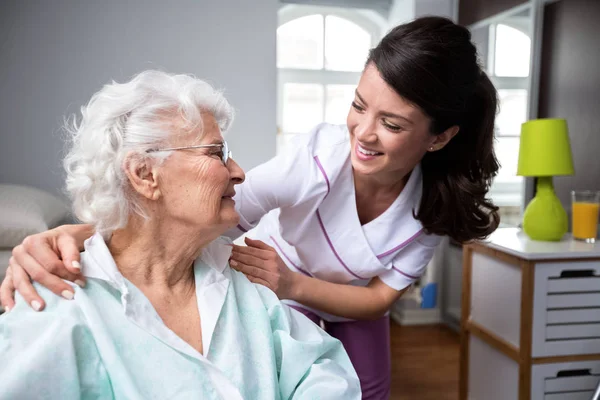 Smiling nurse and old woman patient at wheelchair — Stock Photo, Image