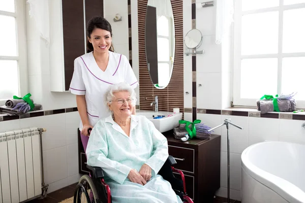 Enfermera ayudando a anciana en silla de ruedas — Foto de Stock