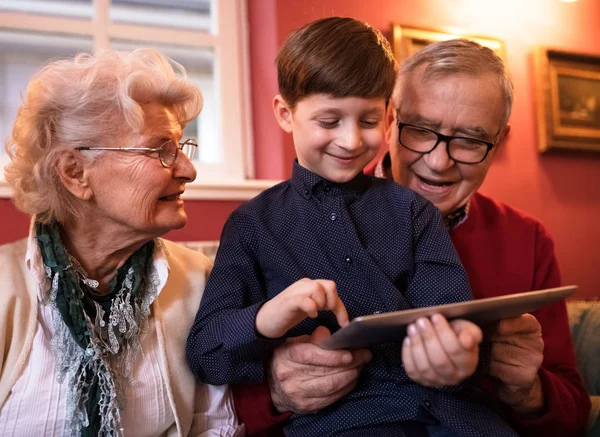 Äldre par avkopplande med deras barnbarn medan du använder tablet — Stockfoto