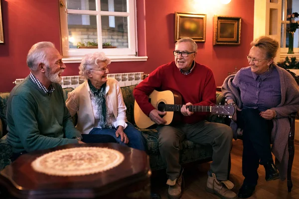 Viejo hombre mayor tocando la guitarra con sus amigos, haciendo gran par — Foto de Stock