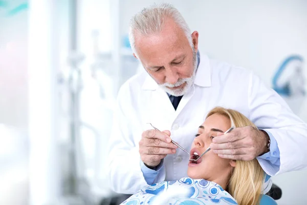 Dokter gigi yang berpengalaman mengulas gigi gadis muda — Stok Foto