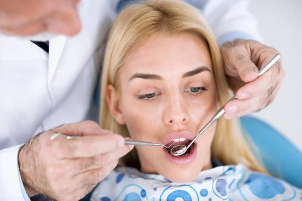 Дантист осматривает зубы пациента у стоматолога — стоковое фото