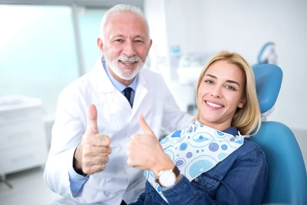 Улыбающийся и довольный опытный стоматолог и молодой пациент на корме — стоковое фото