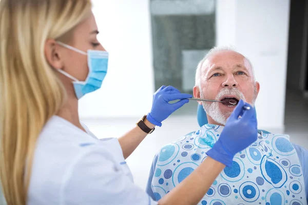Seorang dokter gigi perempuan muda mengontrol kesehatan gigi — Stok Foto