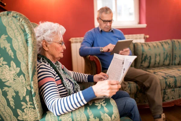 Senior Pareja Encantadora Relajarse Casa Mientras Lee Periódico Uso Tableta — Foto de Stock