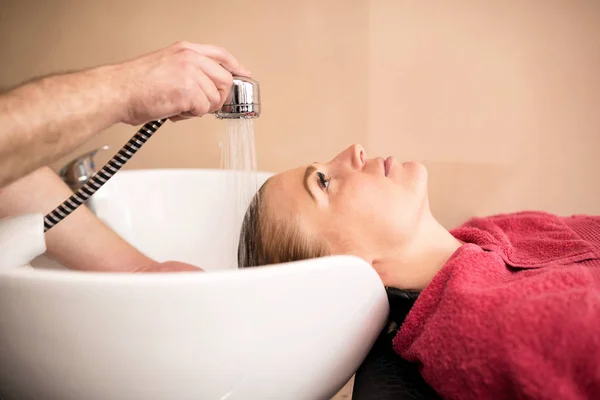 Mulher bonita recebendo lavagem de cabelo em um salão de cabeleireiro — Fotografia de Stock