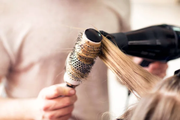Working with comb and hair dryer at beauty salon