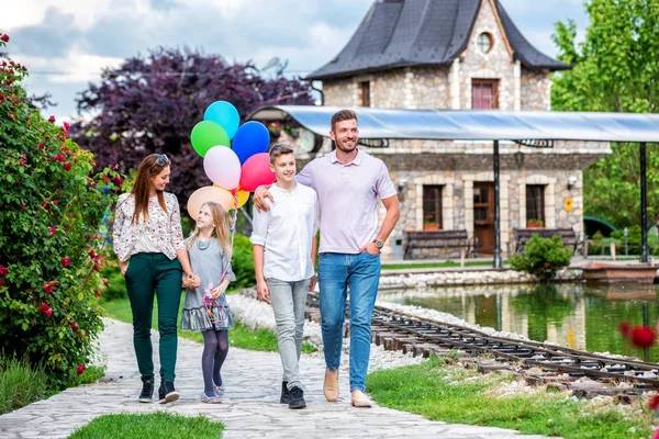 Gadis kecil yang manis membawa balon saat berjalan dengan keluarganya — Stok Foto