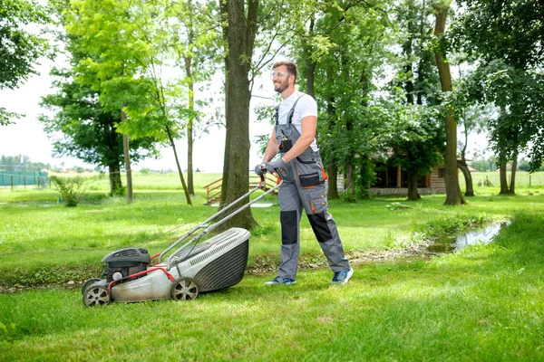 Jardinier coupe herbe avec tondeuse à gazon — Photo