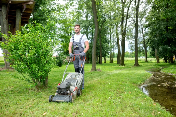 Ung hårt arbetande trädgårdsmästare som håller gräs i ordning — Stockfoto