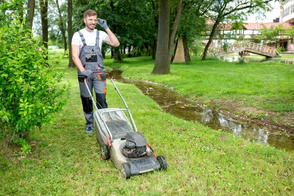 Ung hårt arbetande trädgårdsmästare som håller gräs i ordning — Stockfoto