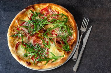 Tasty looking pizza with rocket plant toppings 