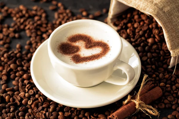 Heart shaped latte art on a coffee bean background — Stok fotoğraf