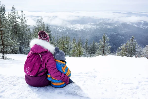 Mother and her child sitting on a snowy bench — Stok fotoğraf