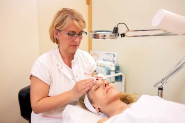 Experienced cosmetician treating her client with gentleness and 