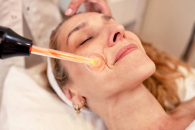 Middle aged woman having a high frequency facial cosmetic treatm