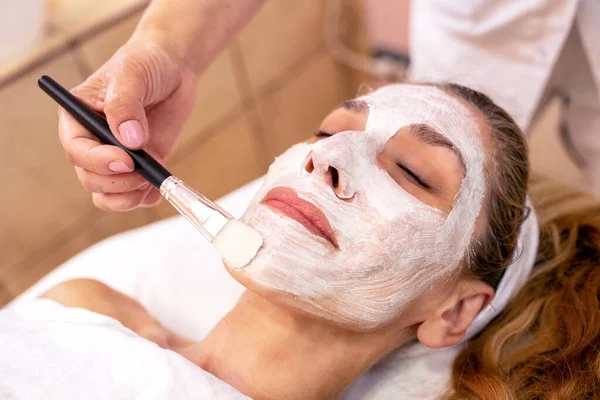 Cosmetician applying a facial layer beauty mask — Stock fotografie