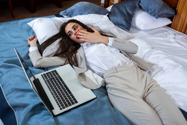 Tired young businesswoman resting on the bed — Stockfoto