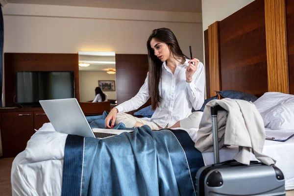 Young elegant lady managing business from bed — Stockfoto