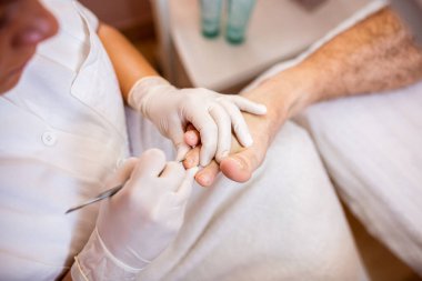 Kozmetikçi kadın ayak tırnaklarıyla uğraşıyor, erkekler pedikür konsepti.