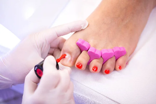 Painting toe nails like a pro, red nail polisher, pedicure concept